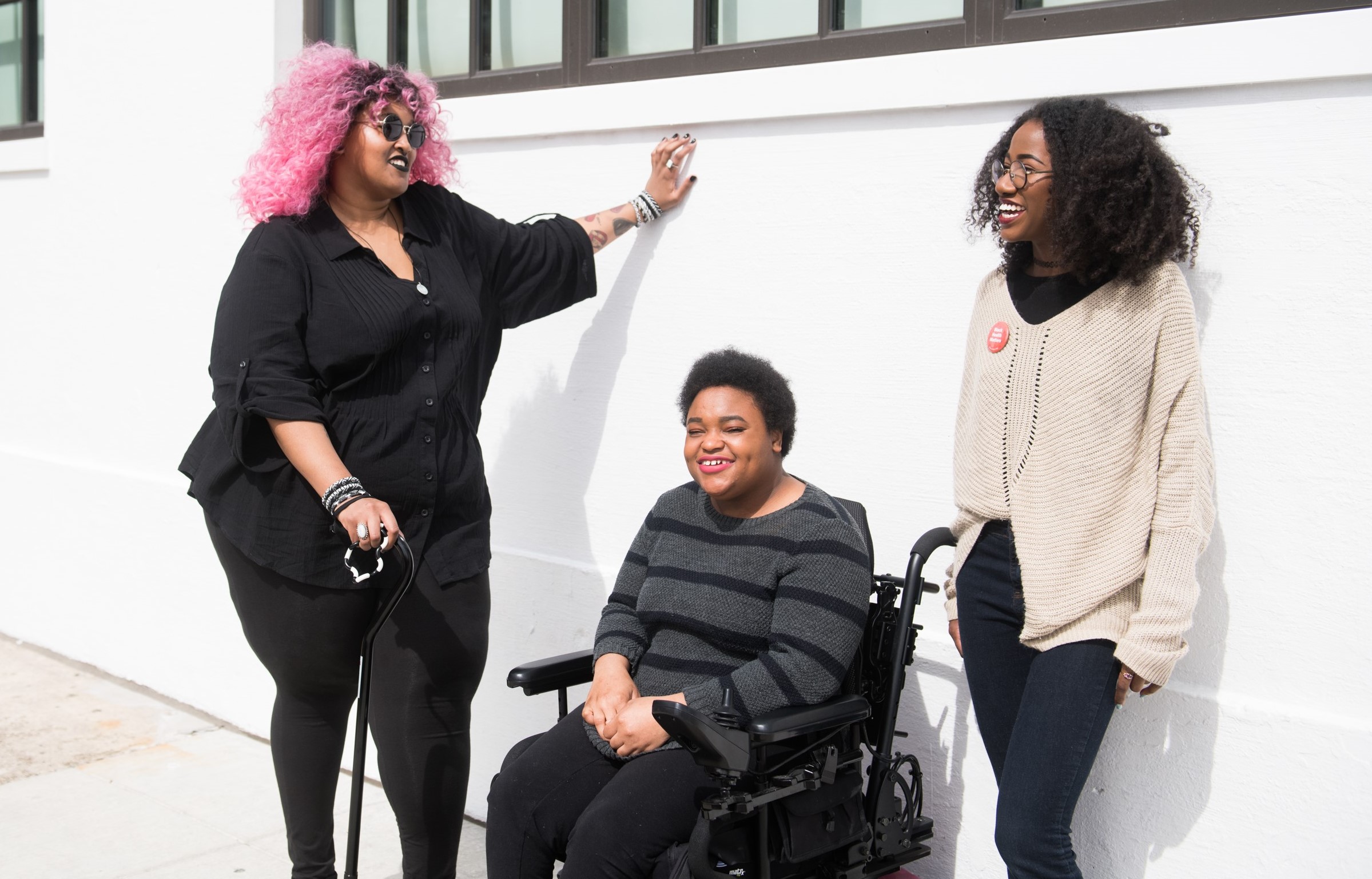 Three Black and disabled friends smiling and taking a selfie.